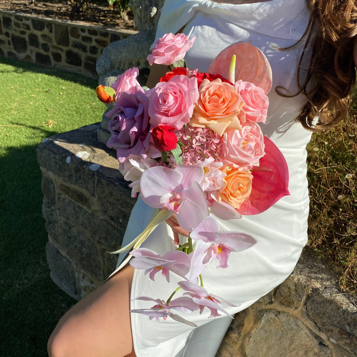 Woman wearing a white dress holding a modern day romance bouquet.