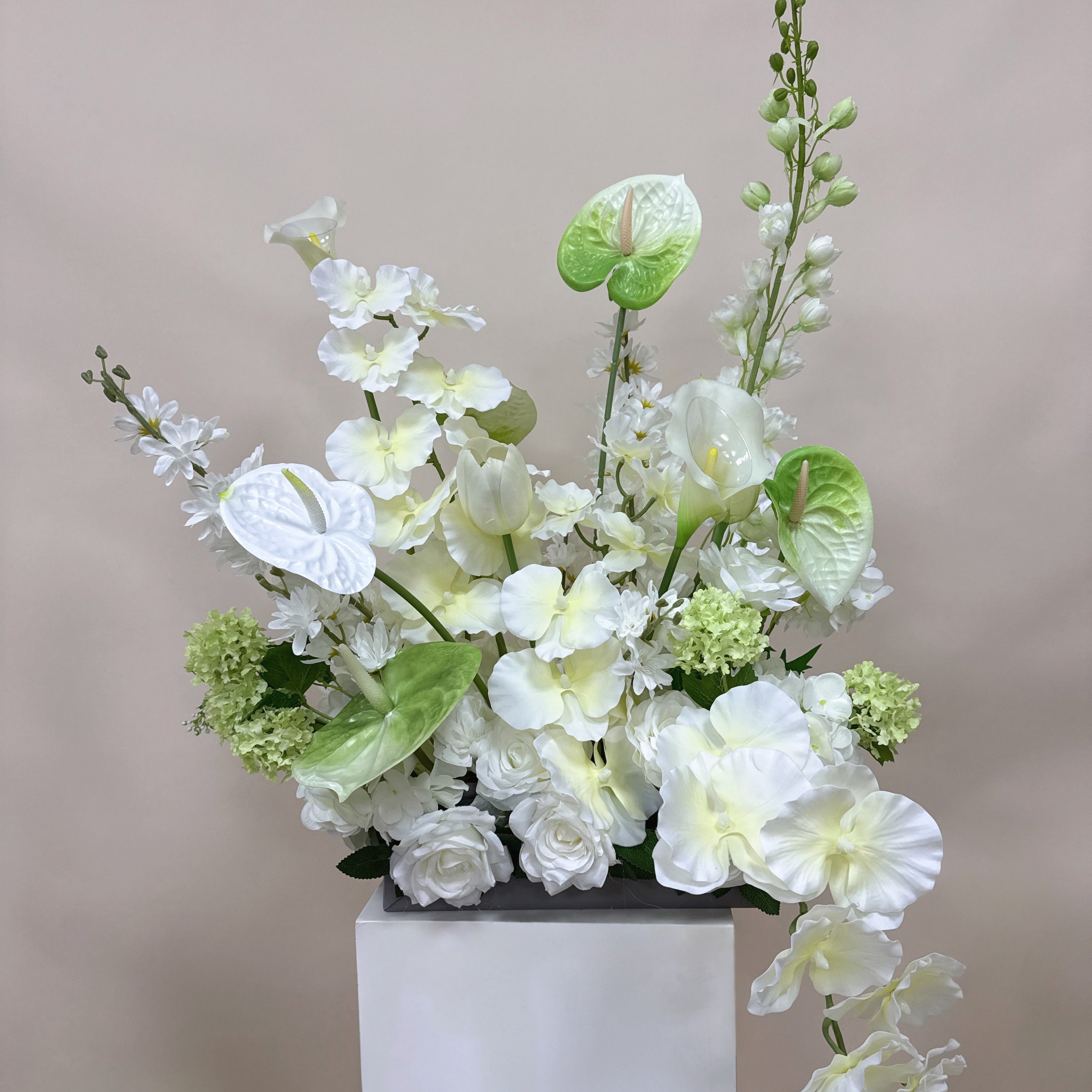 Floral arrangement on a white pedestal against a plain background