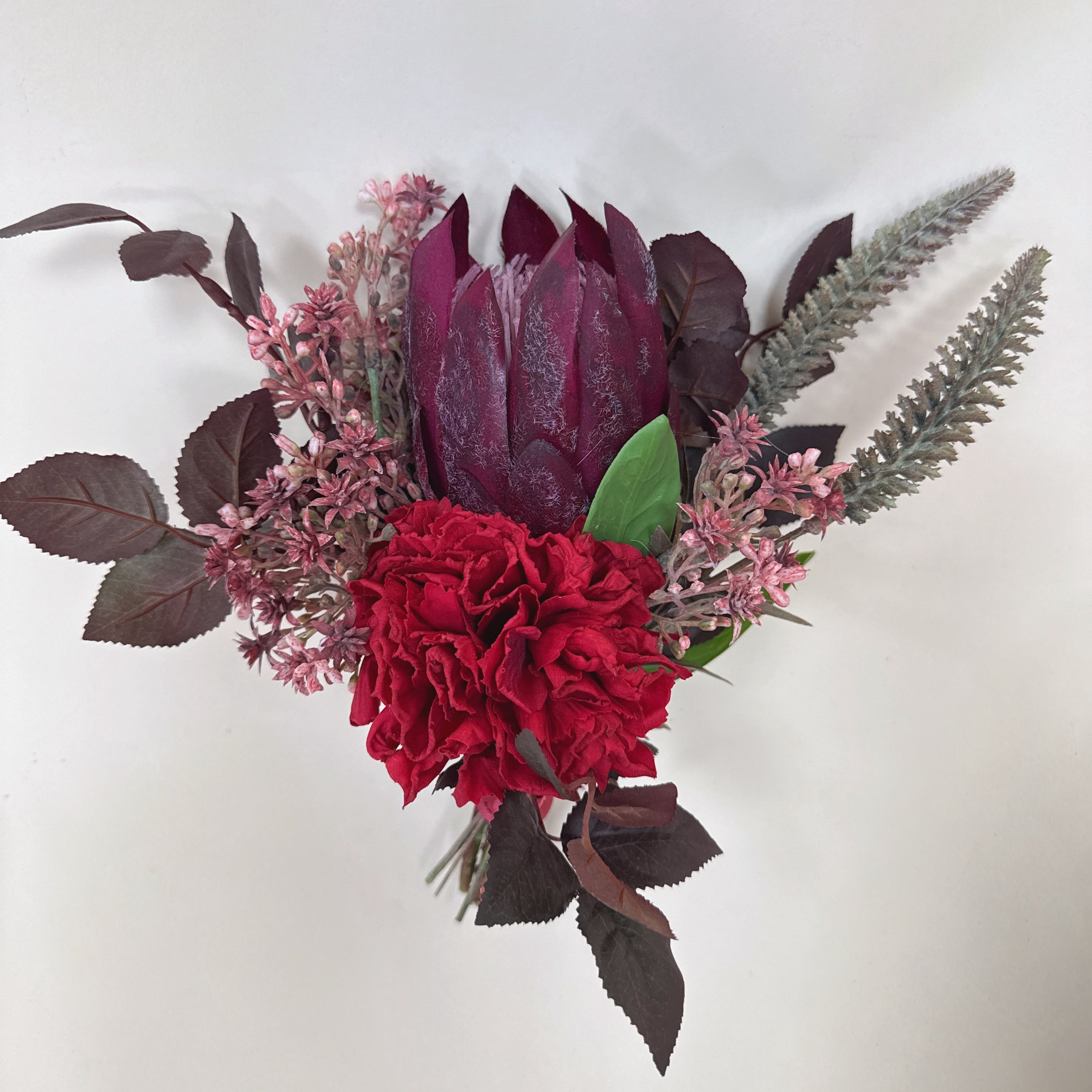 Bouquet of red flowers and purple leaves on a white background
