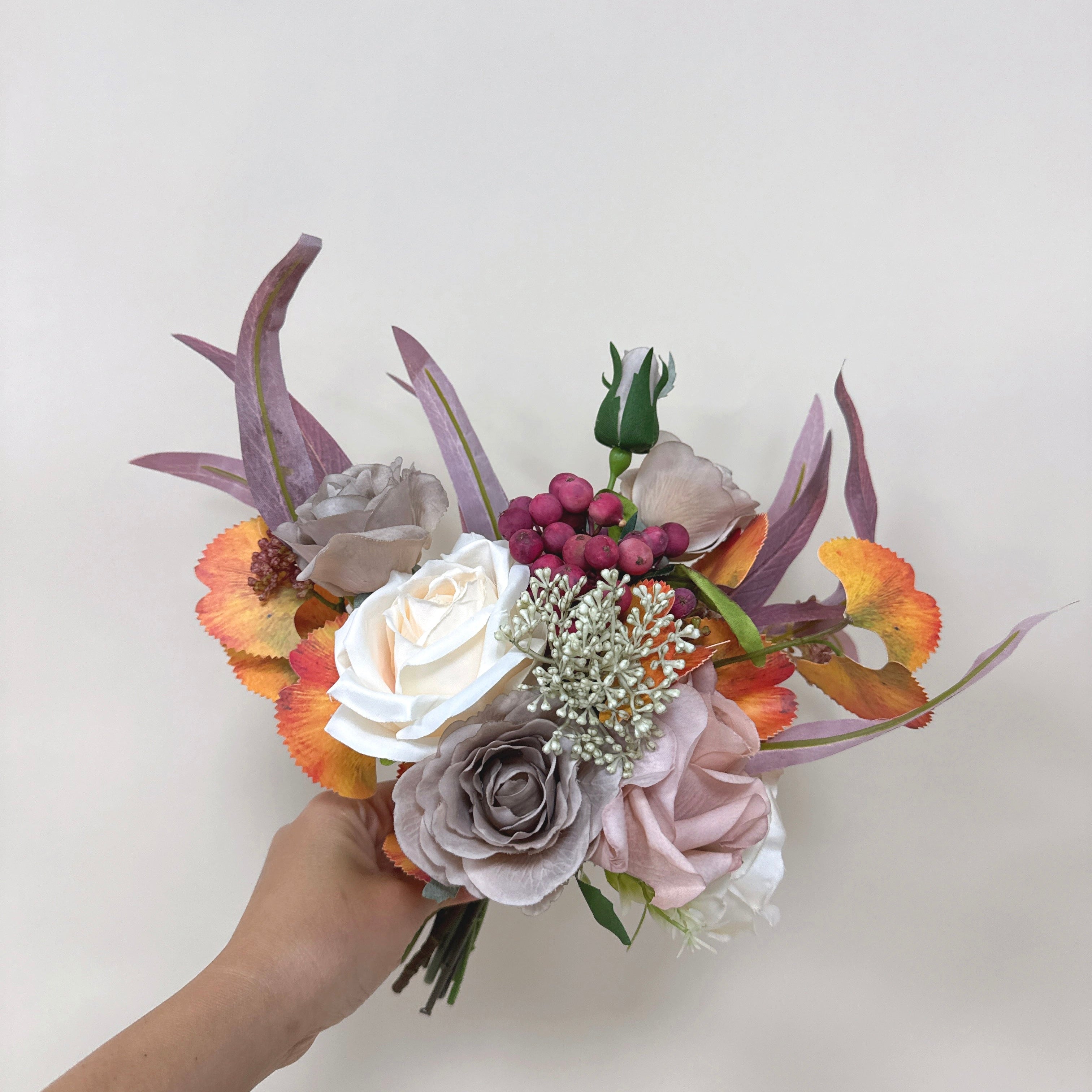 Hand holding a bouquet of flowers with a plain background
