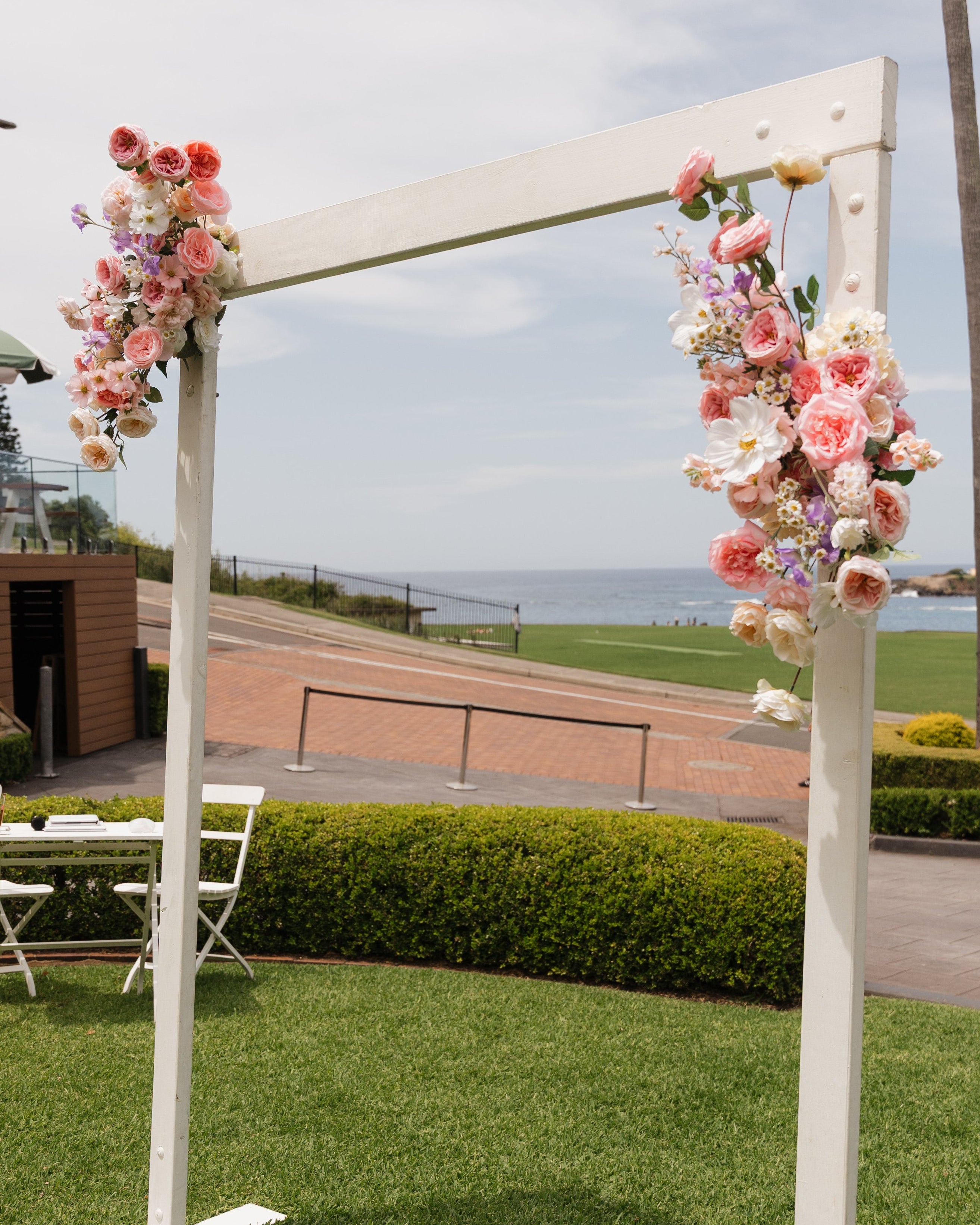 Floral archway on a grassy area with a scenic background