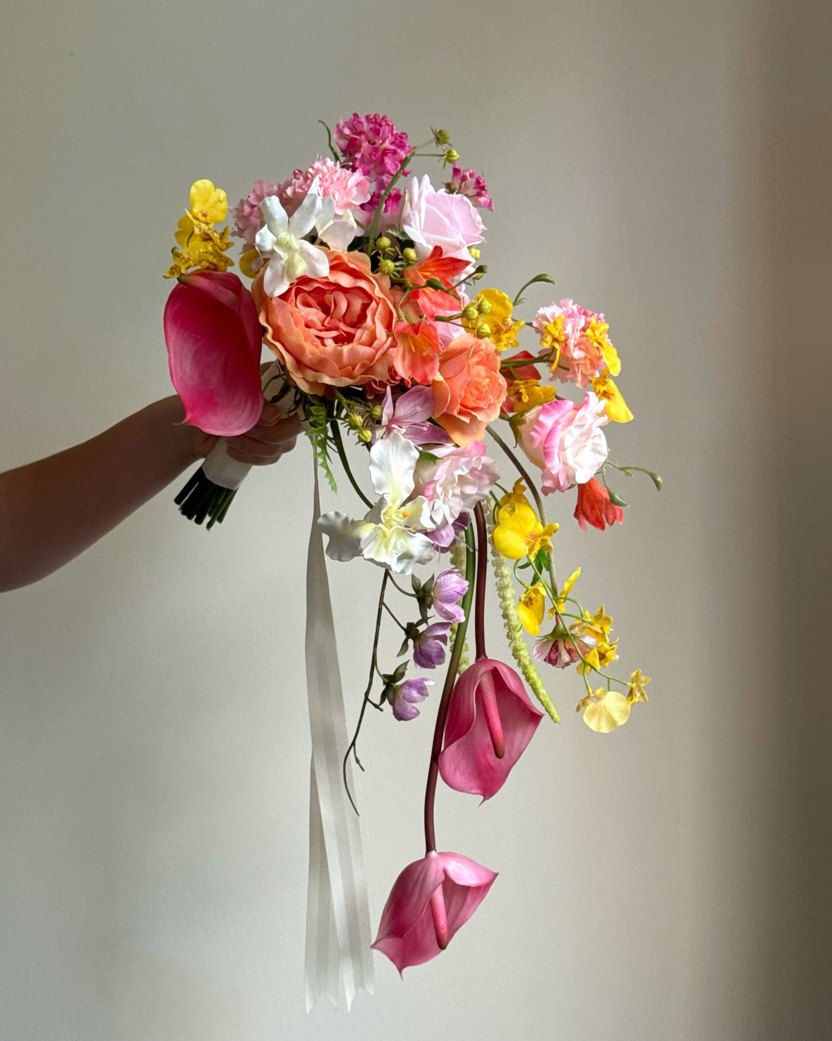 Tropical Punch cascading bouquet featuring bright, colourful real-touch flowers with satin ribbon-wrapped handle.